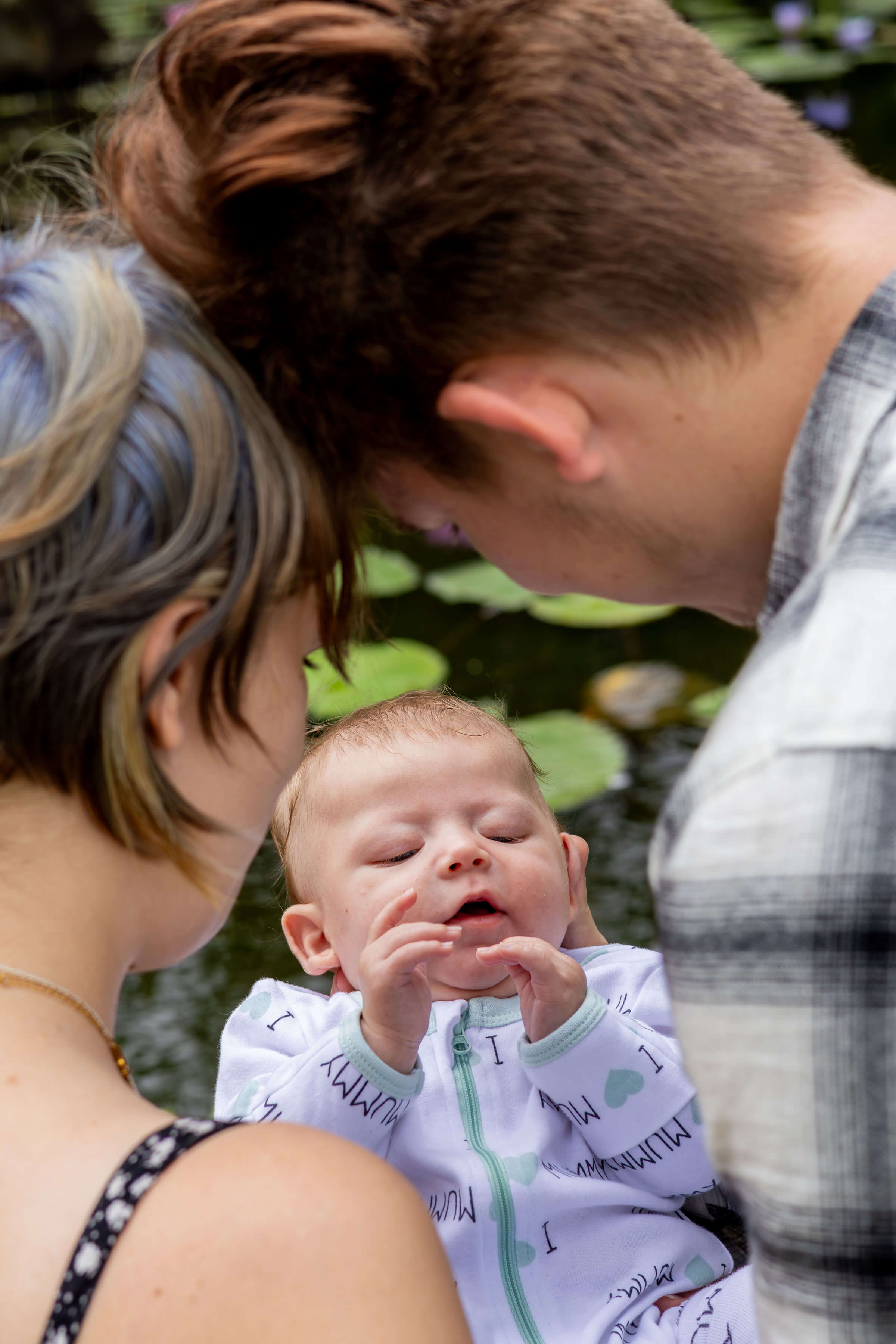 mum and dad looking at their baby in their hands, the camera over their shoulders